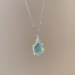 Detail of handmade wire wrapped necklace with light blue stone pendant on silver chain