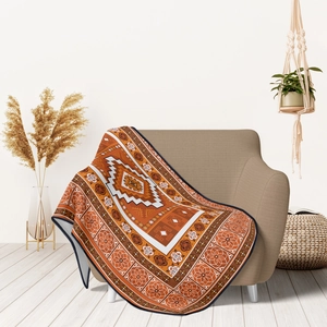 Detailed close-up of bohemian style orange flannel throw blanket on a cozy armchair