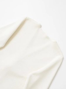 Close-up of cream knit sweater neckline with metal button detail and elegant texture