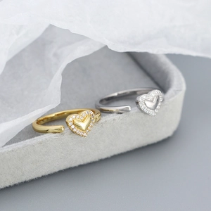 Close-up of heart-shaped adjustable rings in gold and silver with cubic zirconia