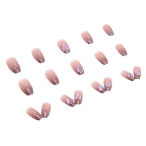 Short ballet press-on nails with nude pink gradient, glitter finish, and 3D purple stones