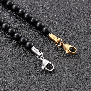 Detailed close-up of black matte beads with gold and silver lobster clasps for jewelry