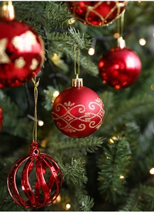 Close-up of red and gold Christmas ball ornaments hanging on a festive green tree