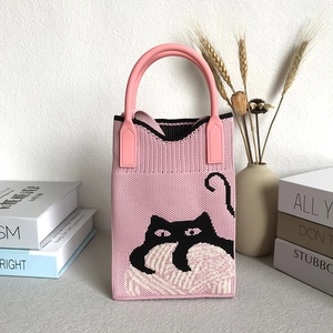 Detail of pink knit tote bag featuring a cute black cat pattern with knitted texture