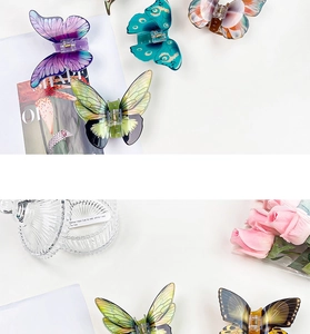 Flat lay of colorful butterfly hair claws on white background with rose and glass box