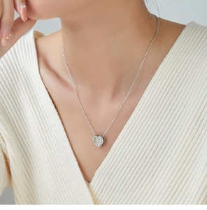 Close-up of a silver heart pendant necklace with shimmering cubic zirconia on model