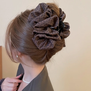 Détail de la pince à cheveux léopard avec texture dentelle élégante sur les cheveux du modèle