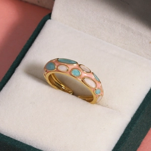Vue macro d'une bague en émail doré avec pierres colorées dans un écrin cadeau