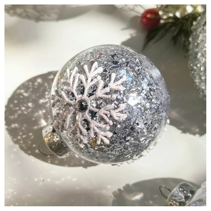Detail view of clear Christmas ornament with silver glitter and white snowflake patterns