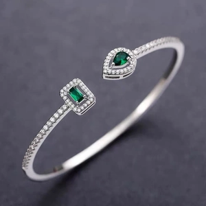 Detailed view of silver open cuff bracelet with teardrop green stone and pavé zircon
