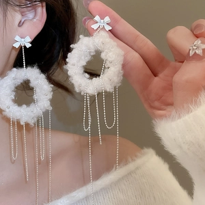 Detailed view of white plush round earrings with bowknot and silver beaded tassels