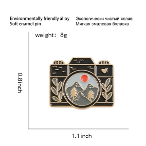 Detail view of camera enamel pin showing dimensions 1.1x0.8 inch and 8g weight specs