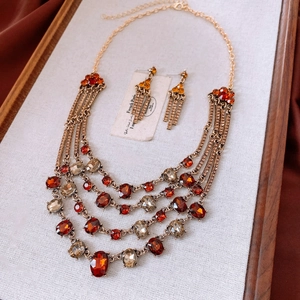 Macro detail of vintage gold-tone jewelry set with red and amber crystals on red silk