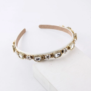 Close-up of pearl and crystal headband with gold filigree details on white stand