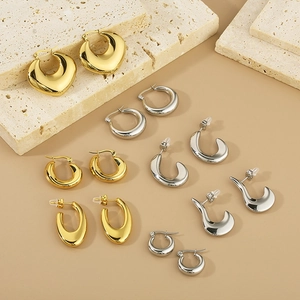 Detailed collection of gold and silver hollow oval geometric earrings on stone props
