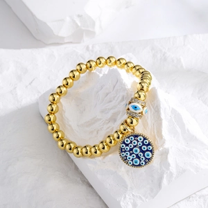 Gold-plated beaded bracelet with sparkling evil eye charm and round enamel pendant