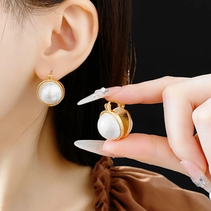 Gros plan détaillé de créoles dorées vintage avec perles blanches portées par un mannequin