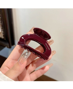 Detailed close-up of a deep red cellulose acetate hair claw with Handmade lettering