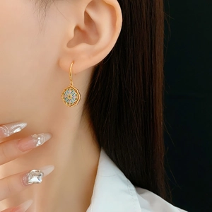 Close-up of vintage gold-plated floral drop earrings with colorful enamel on model