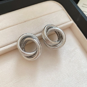 Macro shot of silver interlocking triple ring stud earrings with stardust frosted finish