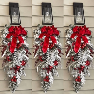 Close-up of snowy flocked Christmas teardrop swag with red velvet bow and berries