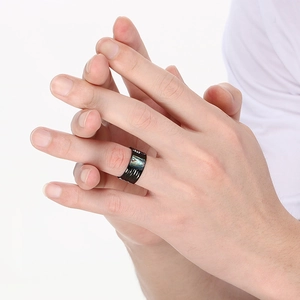 Detailed view of a wide hammered black stainless steel ring featuring colorful abalone shell