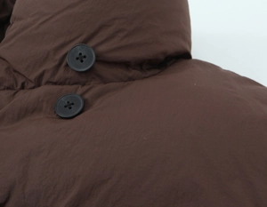 Close-up of dark brown quilted fabric featuring two black buttons and fine stitching