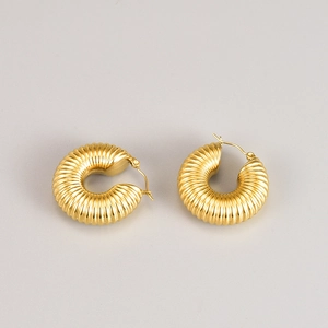 Detail of chunky gold spiral hoop earrings with ribbed texture and click-top closure