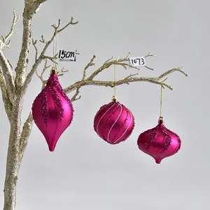 Detail view of rose pink matte Christmas ornaments with glitter spiral patterns and gold strings