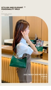Dark green crocodile pattern underarm bag shown on model in a cafe setting