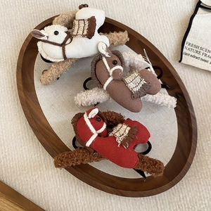 Macro view of plush horse hair clips in creamy white, brown and red on a wooden tray