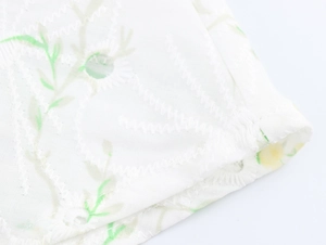 Close-up of white fabric with green floral pattern and wave embroidery texture
