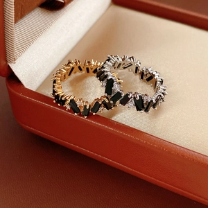 Macro detail of geometric rings with baguette-cut black stones on luxury leather background