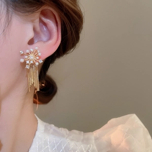 Macro shot of gold tassel earrings with fireworks starburst pearls and zircon crystals