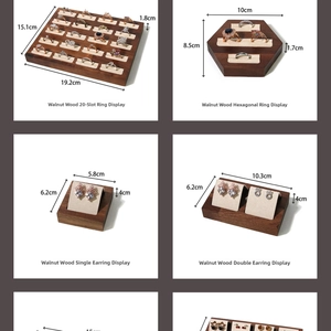Macro detail of walnut wood jewelry display set with beige velvet ring trays and earring stands