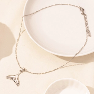 Detailed view of silver whale tail pendant in polished stainless steel on a fine chain