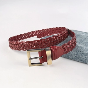 Handwoven dark red braided belt with bronze square buckle on blue denim background