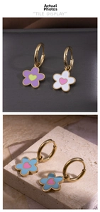 Détail macro de boucles d'oreilles fleurs dorées avec émail coloré et accents de cœur