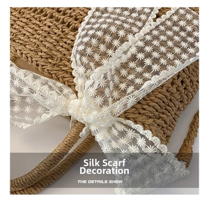 Detailed close-up of straw woven texture and white floral lace ribbon on crossbody bag