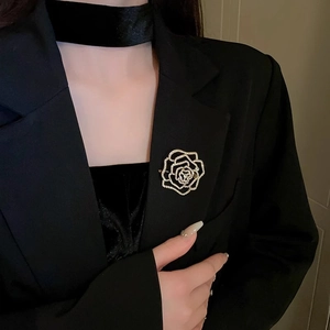 Close-up of gold-plated camellia flower brooch with white zircons on a black blazer