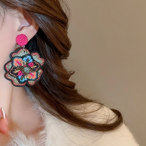 Close-up of handmade floral embroidered earring with colorful beads and sequins on model