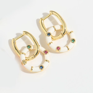 Detail of gold hoops with white enamel rings and multi-colored gemstones in white background