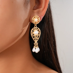 Close-up of gold filigree teardrop earrings with pearls on model in vintage style