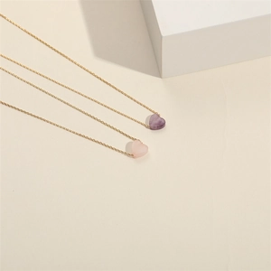 Close-up of heart-shaped amethyst and rose quartz stone pendants on gold chains