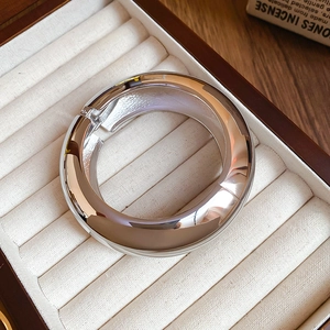 Polished silver adjustable cuff bracelet presented on a cream velvet jewelry tray