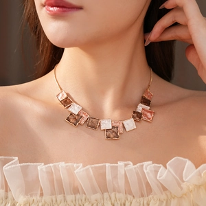 Detail of elegant gold necklace with square resin pendants in brown and cream colors