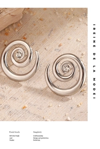 Macro shot of silver spiral metal earrings with sparkling zircon on sandy texture