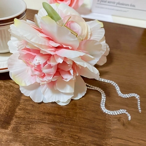 Close-up of fabric flower hair claw with sparkling rhinestone tassels on wooden surface