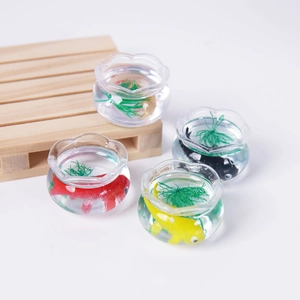 Miniature koi fish tank model with colorful resin fish and green aquatic plants on a wooden tray