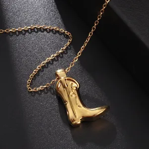 Macro shot of gold cowboy boot pendant showing detailed stitching and polished finish